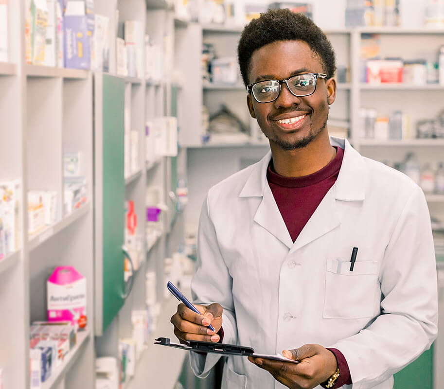 Young male pharmacy technician with a clipboard next to medicine