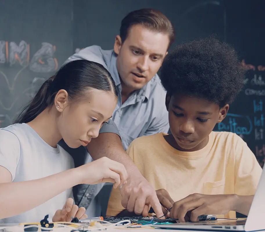 Mentor talk about electric tool while student fixing robotic model. Edification.