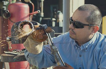 Man welding a pipe outside
