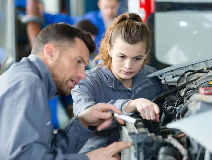 woman as a mechanic apprentice in auto repair shop