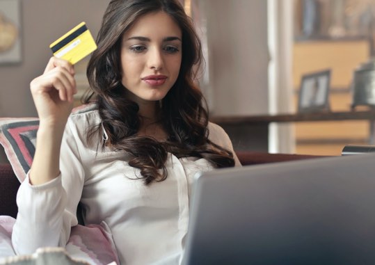 Lady at a laptop computer holding a credit card.