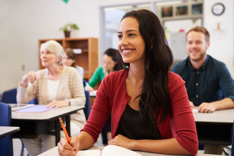 Hispanic woman in a classroom with other students in the background.