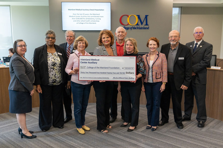 COM board members pose for a photo with Mainland Medical Center Auxiliary members, holding check donated by Mainland Medical Center Auxiliary.