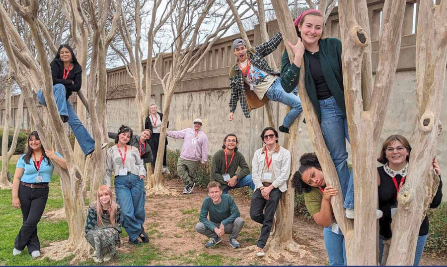 COM Theatre actors outside in trees.