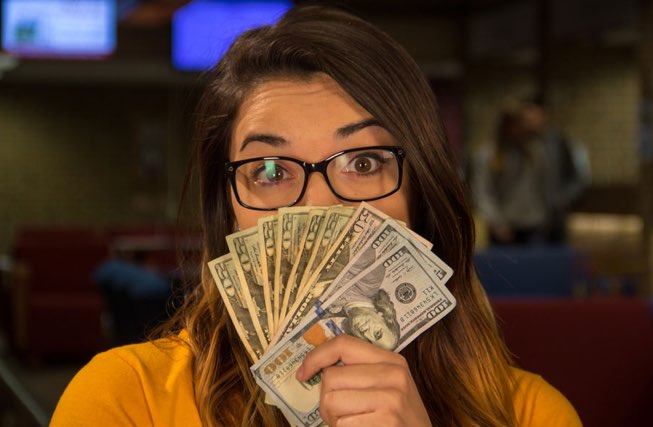 Female student with cash fanned out in front of her face.