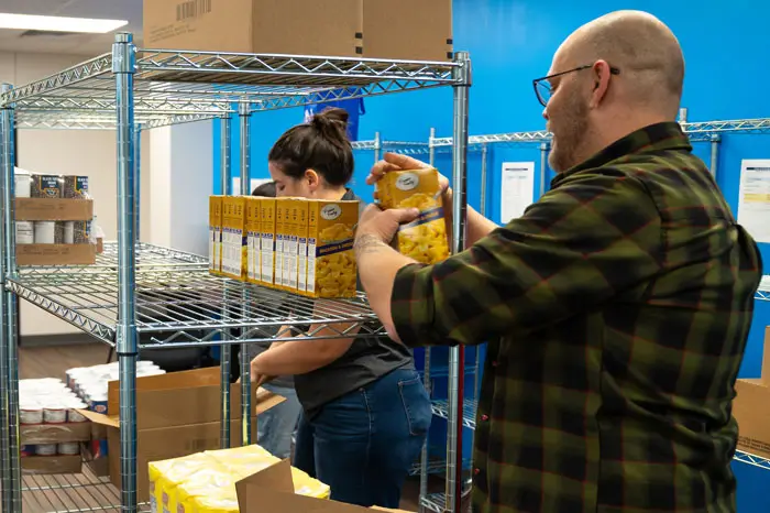 Volunteers setting up shelfs and loading them with food.