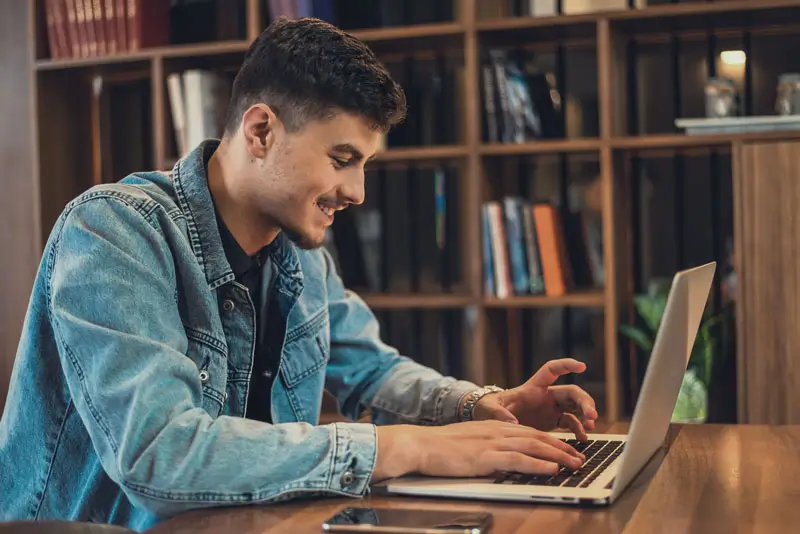 Student typing on laptop in library